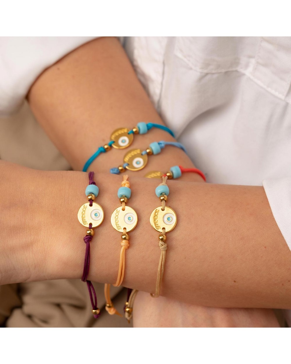 Χειροποίητο βραχιόλι της Excite Fashion Jewellery, μακραμέ, κίτρινο κορδόνι, επίχρυσο μοτίφ με ματάκι και τιρκουάζ χάντρα. B-1771-12 Κοσμήματα