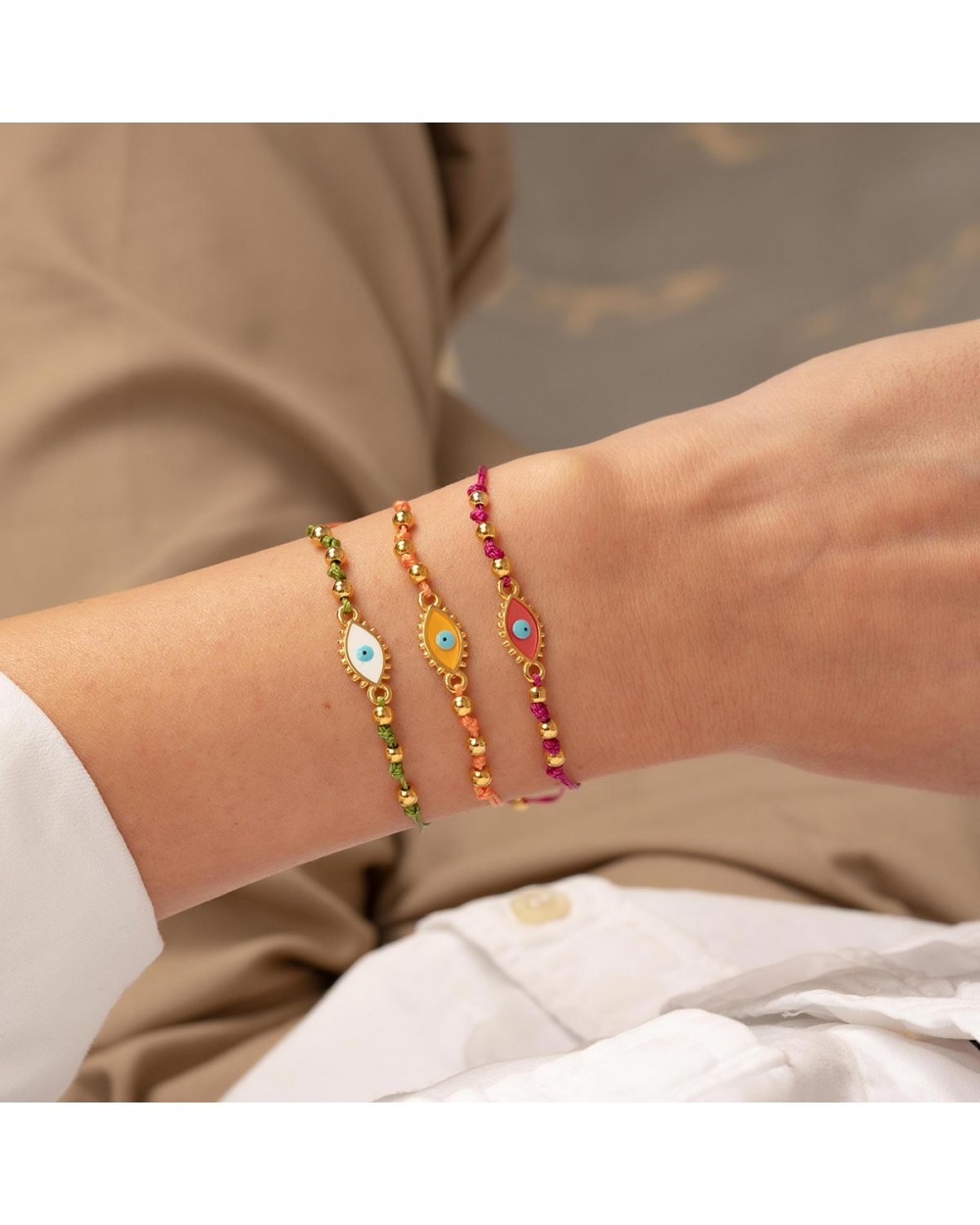 Χειροποίητο βραχιόλι μακραμέ της Excite Fashion Jewellery, πράσινο κορδόνι, οβάλ επίχρυσο ματάκι με λευκό σμάλτο B-1784-08, και χρυσές μπίλιες. Κοσμήματα